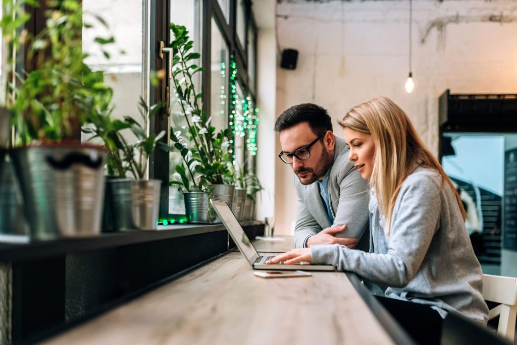 Woman and a man looking at the laptop screen, researching Bay Area movers
