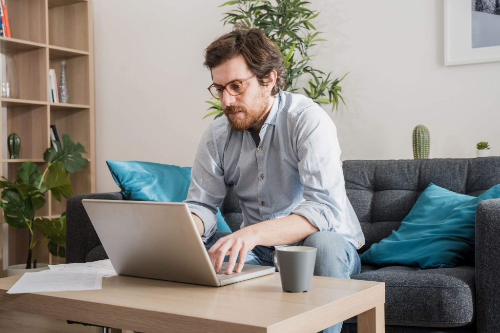 Man sitting on the couch, typing on the laptop
