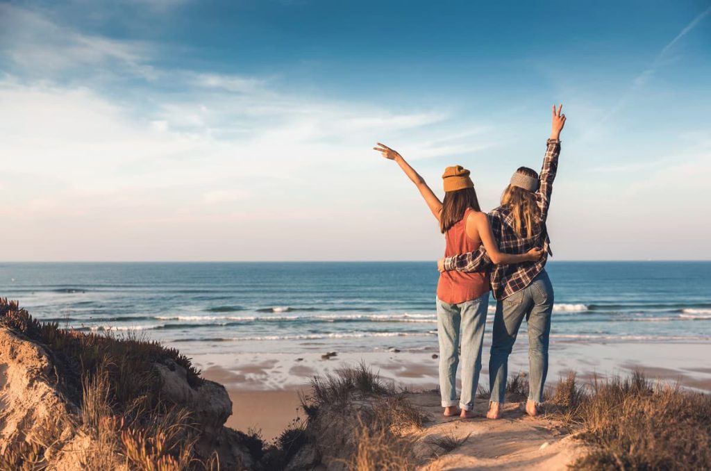 Two women holding each other and looking at the ocean